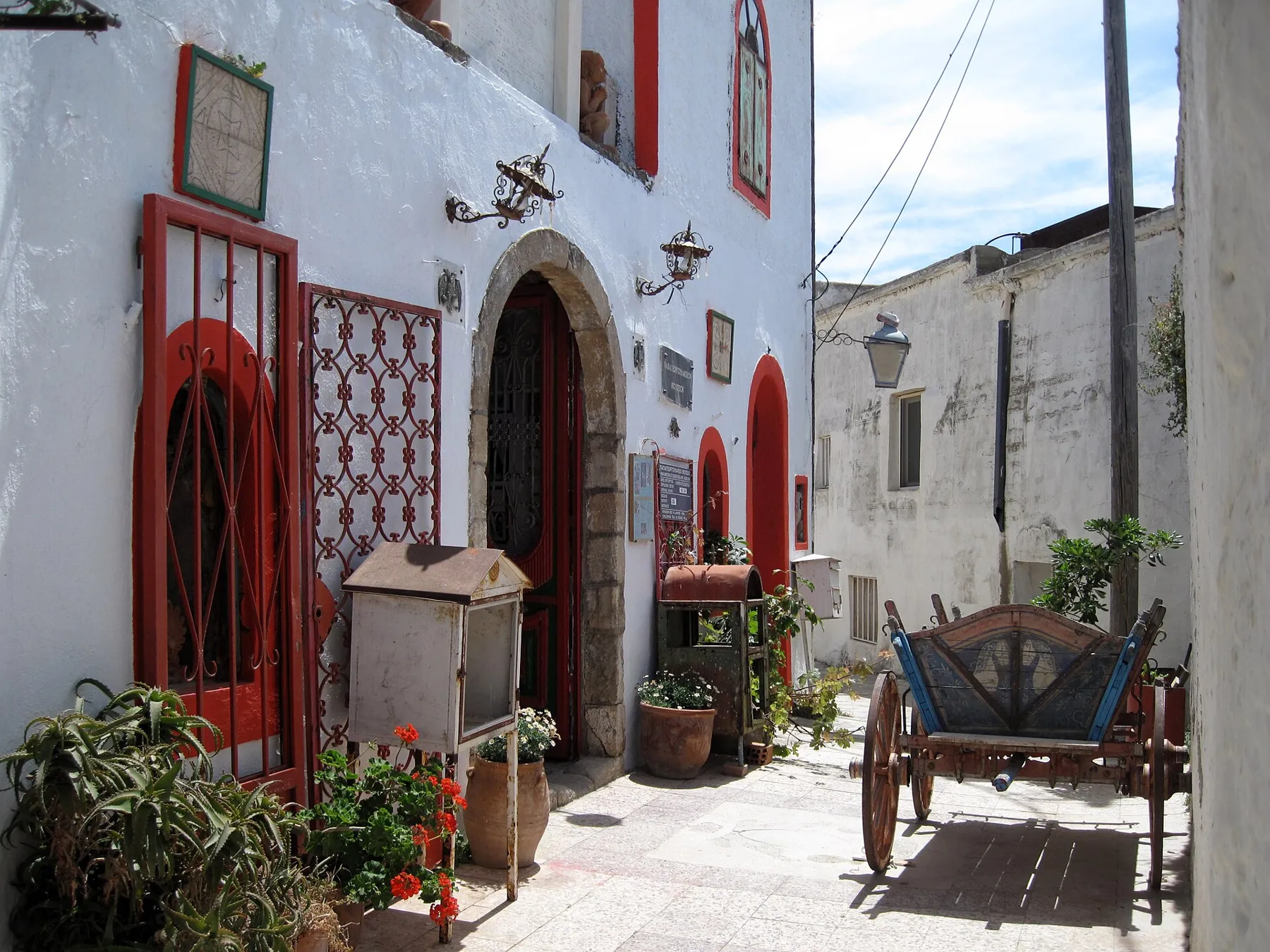 A lane in Asomatos village with a painted doorway and an old cart