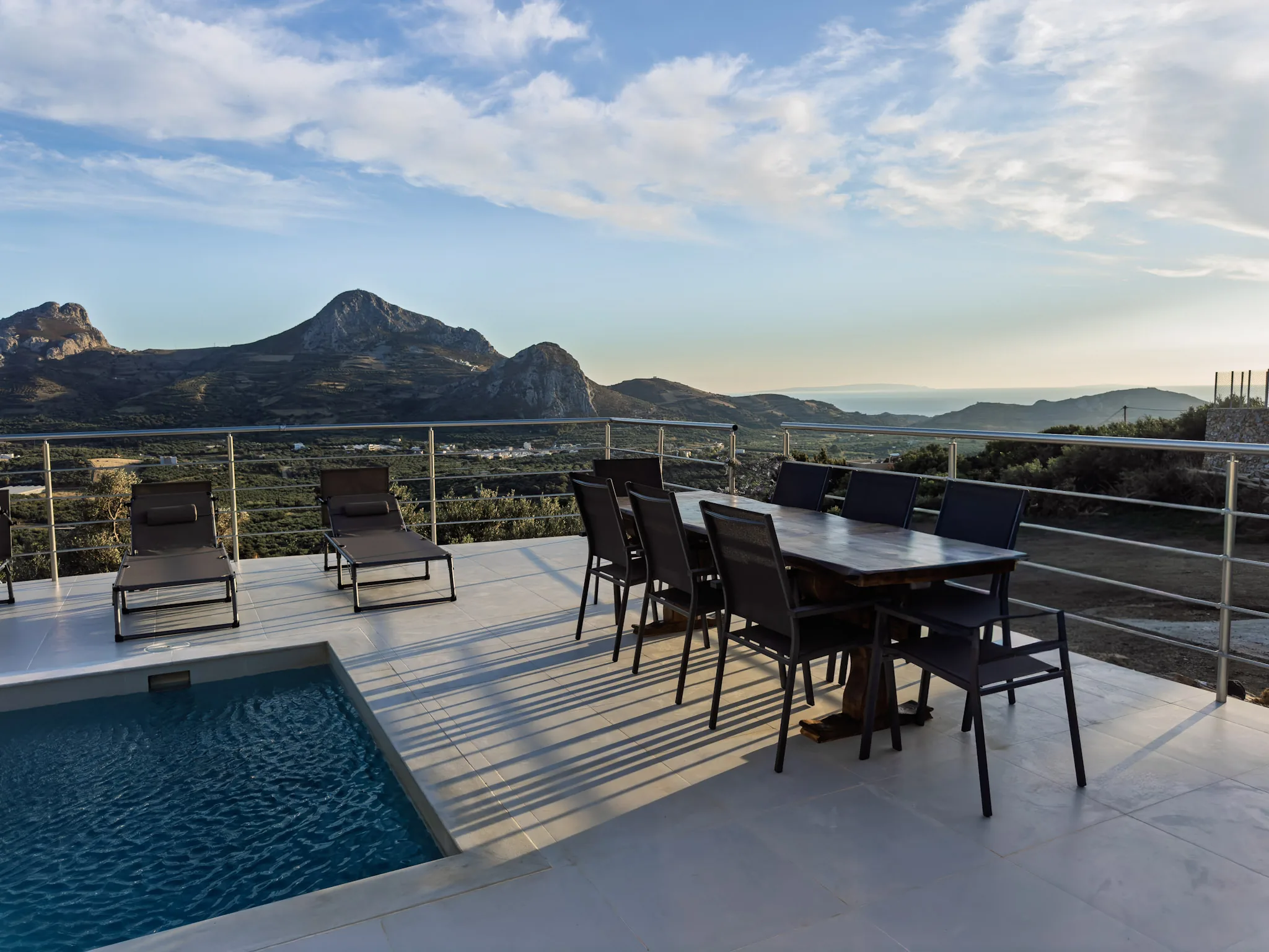 Pool terrace with dining table and loungers facing the valley